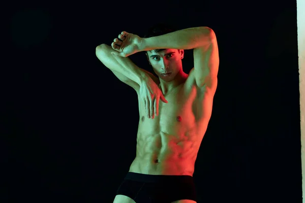 性感的运动员健美运动员鼓起了躯干，双手紧握着后脑勺，在黑色的背景下进行着剪影 — 图库照片