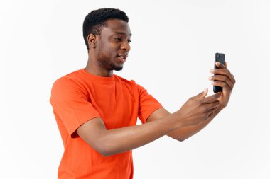 Turuncu tişörtlü Afrikalı bir adam açık arkaplan görünümlü Model Kopya Boşluğu