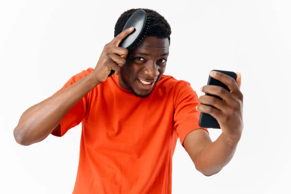 Homem penteando sua cabeça africana aparência telefone na mão — Fotografia de Stock