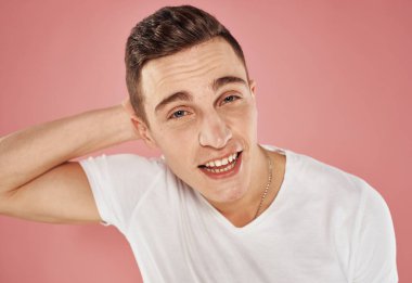 Pembe arka planda neşeli bir adamın portresi beyaz tişört duygularının kırpılmış görüntüsüydü.