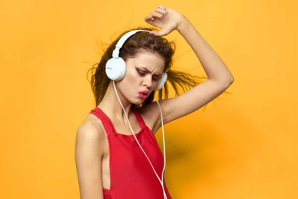 Femme joyeuse dans les écouteurs écoute de la musique dans un fond rouge T-shirt jaune — Photo