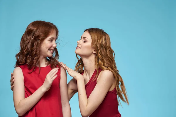 Aile annesi ve kızı sarılır kırmızı elbiseler iletişim duyguları mavi arka plan — Stok fotoğraf