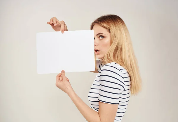 Femme en t-shirt rayé cheveux blonds et une feuille blanche de papier sur fond beige — Photo