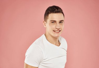 Neşeli adam el duygularıyla jestler yapıyor beyaz tişört pembe arka plan