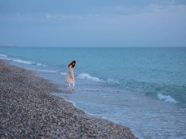 Kadın deniz kıyısında doğa ve kumsal mavi gökyüzünde seyahat eder.