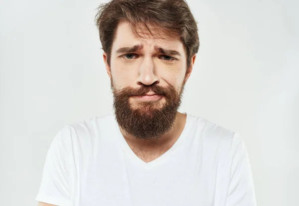 Bearded man i en vit T-shirt på en lätt bakgrund sorgligt ansikte känslor skägg — Stockfoto