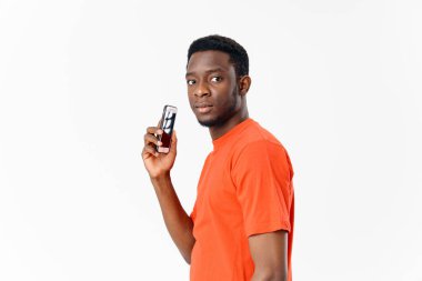 Turuncu tişörtlü cep telefonlu adam. Yeni teknoloji yan görünümü.