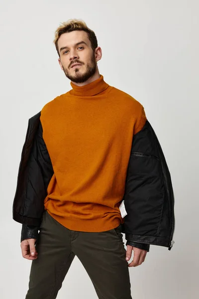 Sexy hombre en suéter y chaqueta de cuero posando sobre fondo claro recortado vista — Foto de Stock