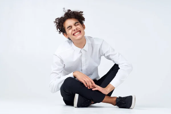 Cara Com Cabelo Encaracolado Uma Camisa Branca Tênis Calças Senta — Fotografia de Stock