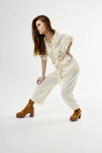 Kvinna hålla hennes bälte vit overall studio brun stövlar — Stockfoto
