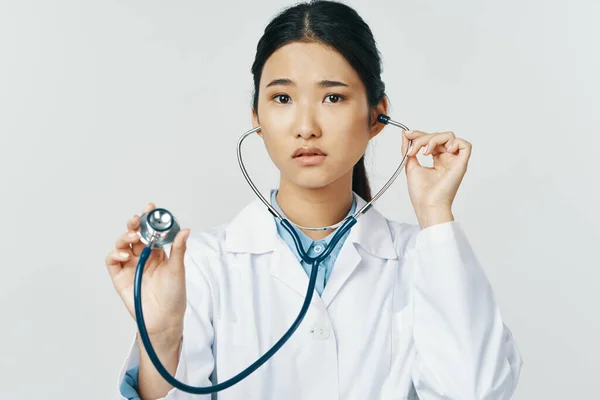 Азійська жінка - лікар у медичній сукні зі стетоскопом у руці. — стокове фото