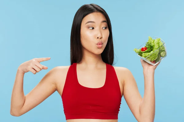 Sottile asiatico donna con insalata in un piatto mostra il suo dito per il lato copia spazio — Foto Stock