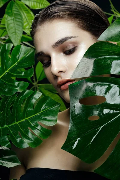 Hermosa mujer entre hojas de palma en la naturaleza maquillaje ojos cerrados — Foto de Stock