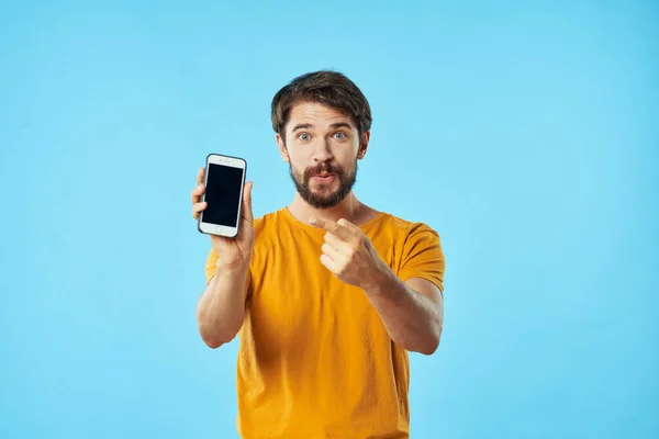 Man met mobiele telefoon gebaren met zijn handen op een blauwe achtergrond Copy Space — Stockfoto
