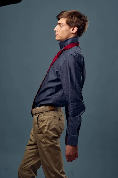 Jonge man in klassiek pak shirt en broek op grijze achtergrond bekijken — Stockfoto