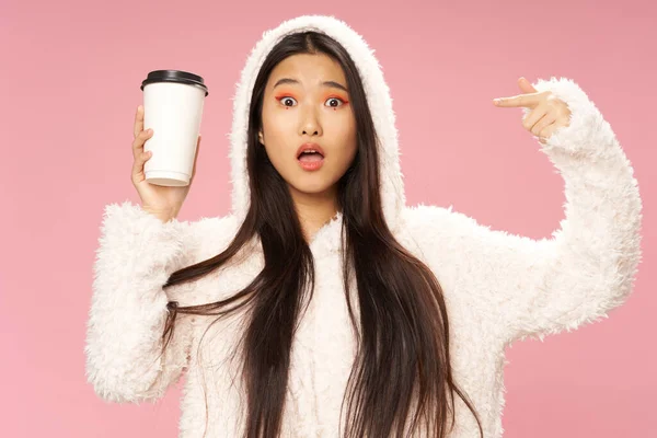 Femme asiatique dans une veste chaude avec une capuche tient une tasse de café chaud dans sa main — Photo