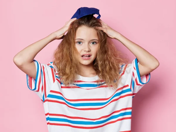 Мила дівчина кучеряве волосся модний одяг рожевий фон студії — стокове фото