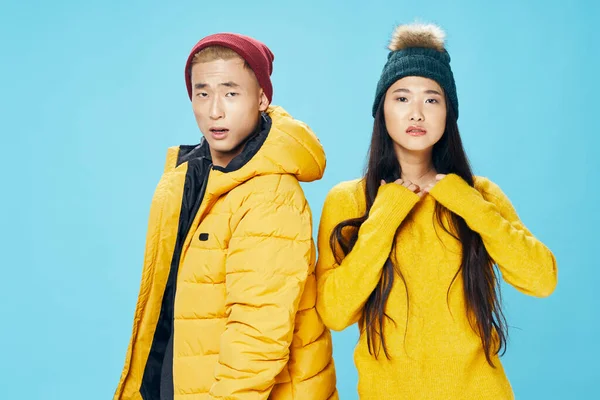 Chico en caliente chaqueta y mujer en suéter y sombrero en azul fondo moda ropa amigos asiático familia — Foto de Stock