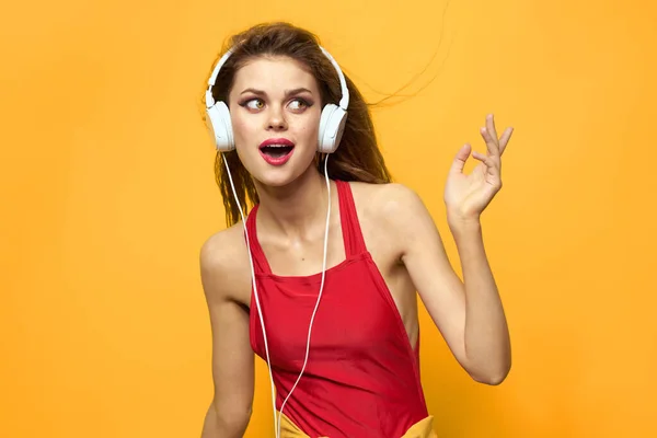 Mujer en auriculares escuchando música rojo camiseta emociones moda amarillo fondo estilo de vida —  Fotos de Stock