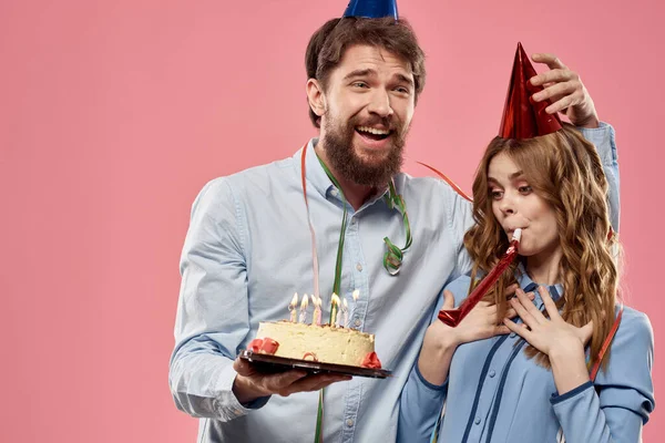 Party man and woman with cake on pink background corporate birthday