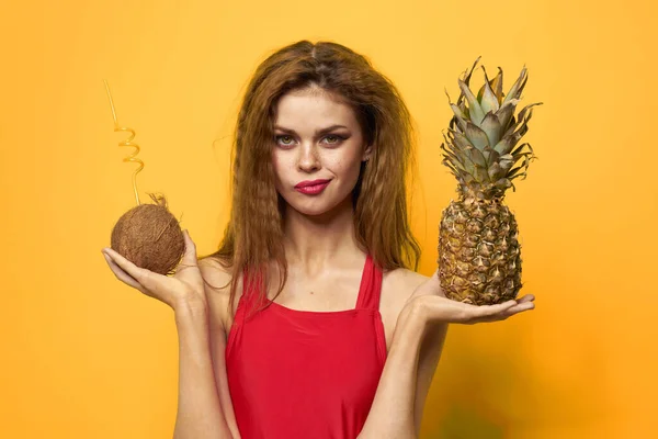 Γυναίκα με καρύδα κοκτέιλ Ανανάς στα χέρια και τα κρίσιμα φρούτα Κόκκινο t-shirt κίτρινο φόντο — Φωτογραφία Αρχείου