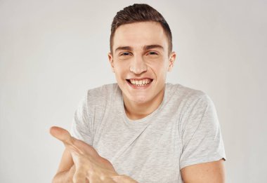 Beyaz tişörtlü neşeli bir adam elleri ve duyguları birbirine yakın hareket eder.