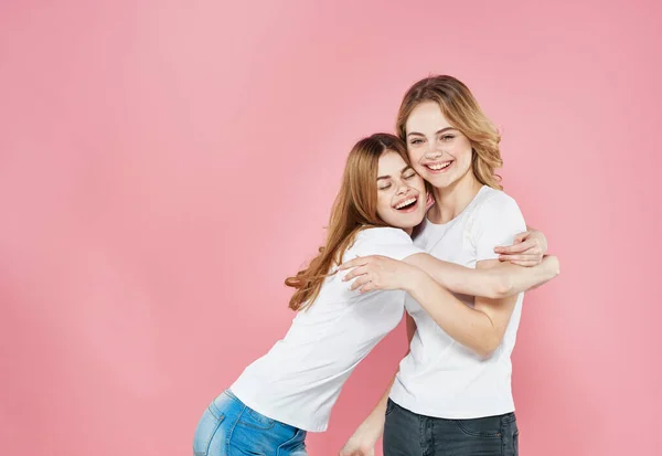 Dos mujeres ropa de moda Amistad abrazos de fondo rosa —  Fotos de Stock
