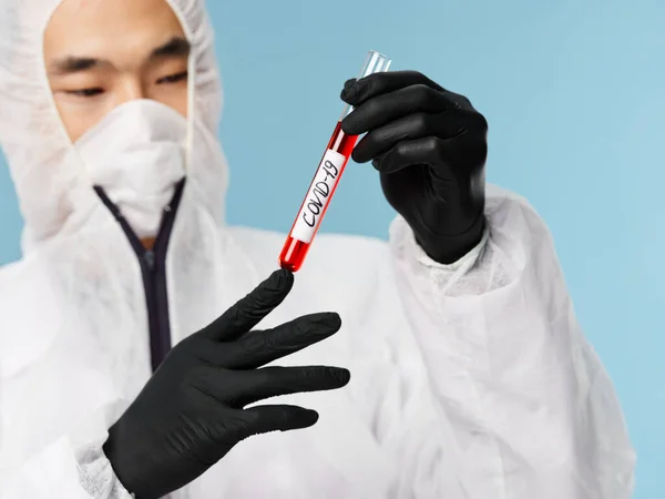 Asiatico maschio uomo indumenti protettivi nero guanti sangue test esame blu fondo — Foto Stock