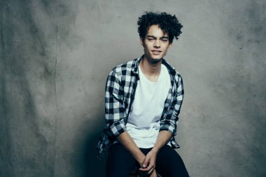 Stüdyoda ekose gömlek giyen neşeli, kıvırcık saçlı adam.