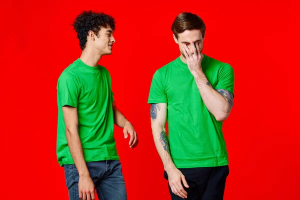 Due amici allegri in t-shirt verdi gioia della comunicazione sfondo rosso — Foto Stock