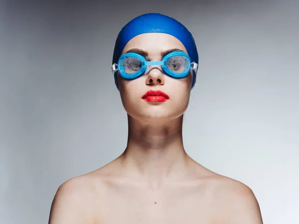 Vista frontale di una donna con un cappello da bagno blu e occhiali su uno sfondo grigio — Foto Stock