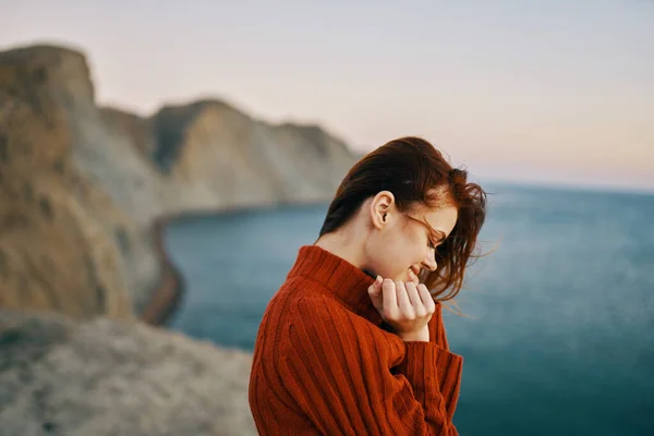 Donna in un maglione gesti con le mani all'aperto in montagna vicino al mare — Foto Stock