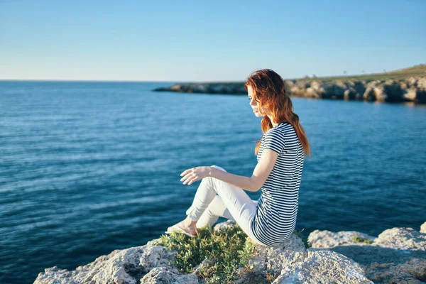 Kadın deniz kenarındaki bir kayanın üzerinde. Yaz günbatımında. — Stok fotoğraf