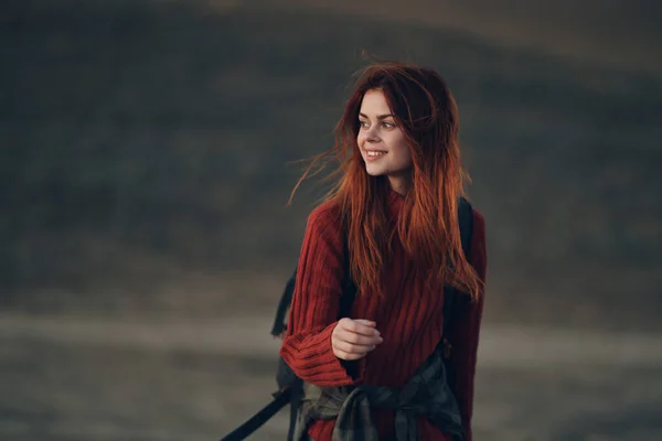 Jolie femme dans un pull avec un sac à dos marchent dans la nature dans les montagnes sur une prairie — Photo