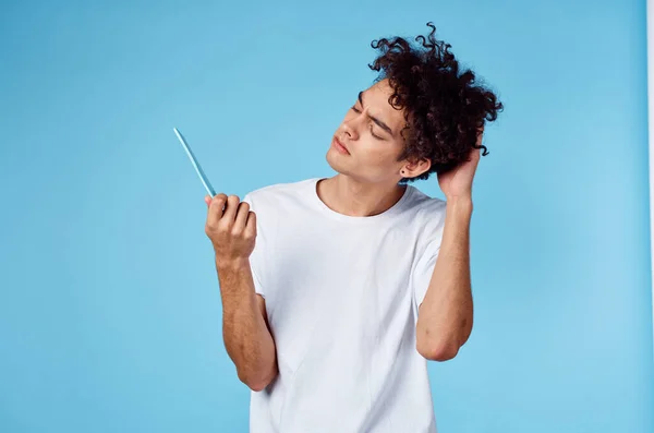 Schattig man met krullend haar houden kam in de hand en blauwe achtergrond bijgesneden uitzicht — Stockfoto