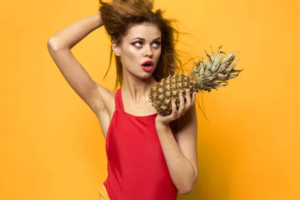 Mulher bonita com abacaxi em suas mãos cosméticos frutas exóticas fundo amarelo divertido — Fotografia de Stock