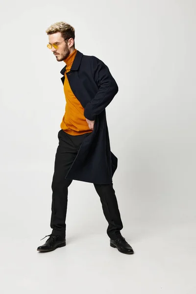 Cara em uma camisola laranja e calças casaco modelo penteado emoções luz fundo — Fotografia de Stock