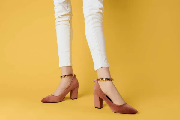 Patas femeninas pantalones blancos ropa de moda zapatos de lujo fondo amarillo — Foto de Stock