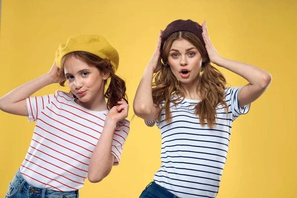 Divertido mamá e hija usando sombreros moda diversión alegría familia amarillo fondo —  Fotos de Stock