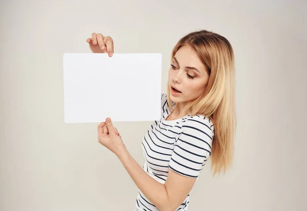 Donna a righe T-shirt capelli biondi e un foglio bianco di carta su uno sfondo beige — Foto Stock