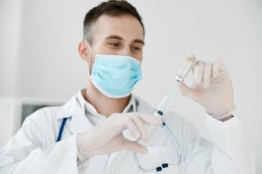 Laboratuvardaki doktor elinde bir şırınga tutuyor. Tıbbi maske aşısı sıvısı.