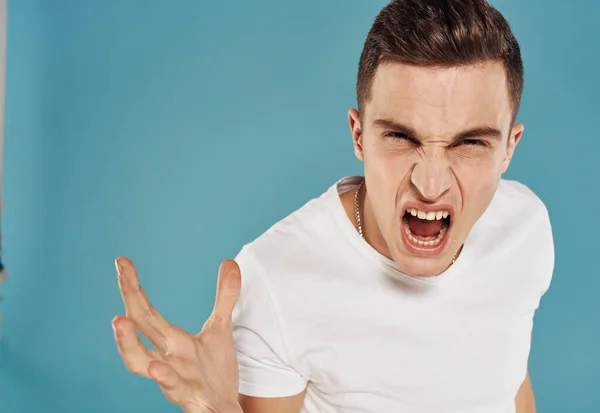 Homme en colère en t-shirt blanc geste avec les mains mécontentement fond bleu — Photo