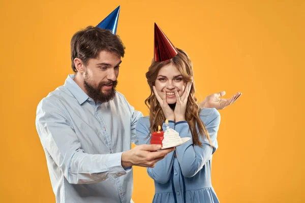 Man and woman in festive caps birthday series yellow background — Stock Photo, Image