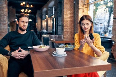 Lokantada oturup yemek yiyen neşeli genç bir çift.