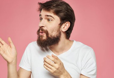 Kafası karışmış, elleri yana bakan, pembe arka planı olan bir adam.
