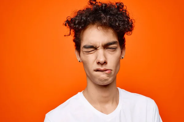 Söt kille i vit t-shirt lockigt hår grimace orange bakgrund — Stockfoto