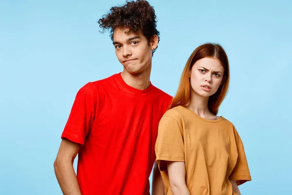 Wesoły młody para w kolorowe t-shirty komunikacyjne studio niebieskie tło — Zdjęcie stockowe