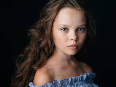 Güzel bebek mavi gözlü kız, siyah arka planda kıvırcık saçlı.