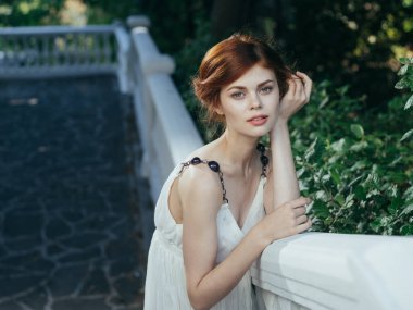 Beyaz elbiseli güzel kadın doğada poz veriyor. 