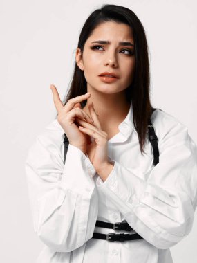 Siyah askılı beyaz gömlekli bir kadın yüzü kesilmiş bir şekilde el ele tutuşuyor.